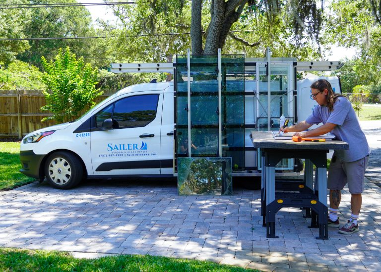 Technician at a workbench beside the Sailer Window Repairs van