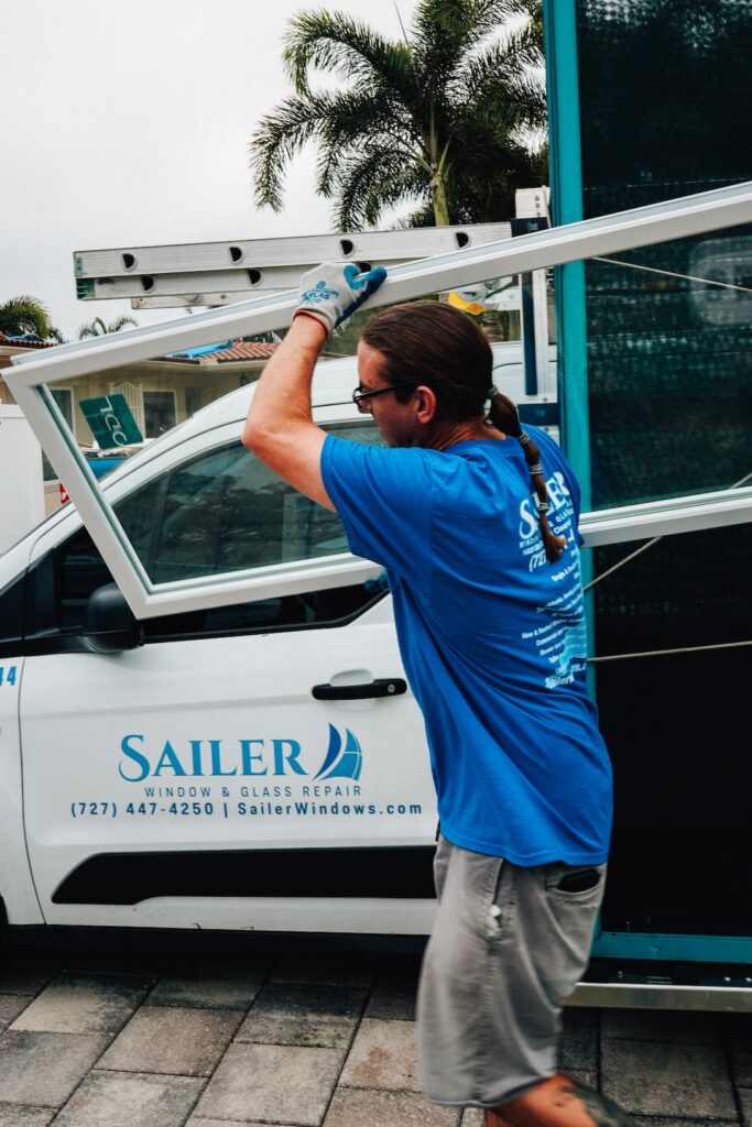 Technician lifting a window sash beside the Sailer Window Repairs van